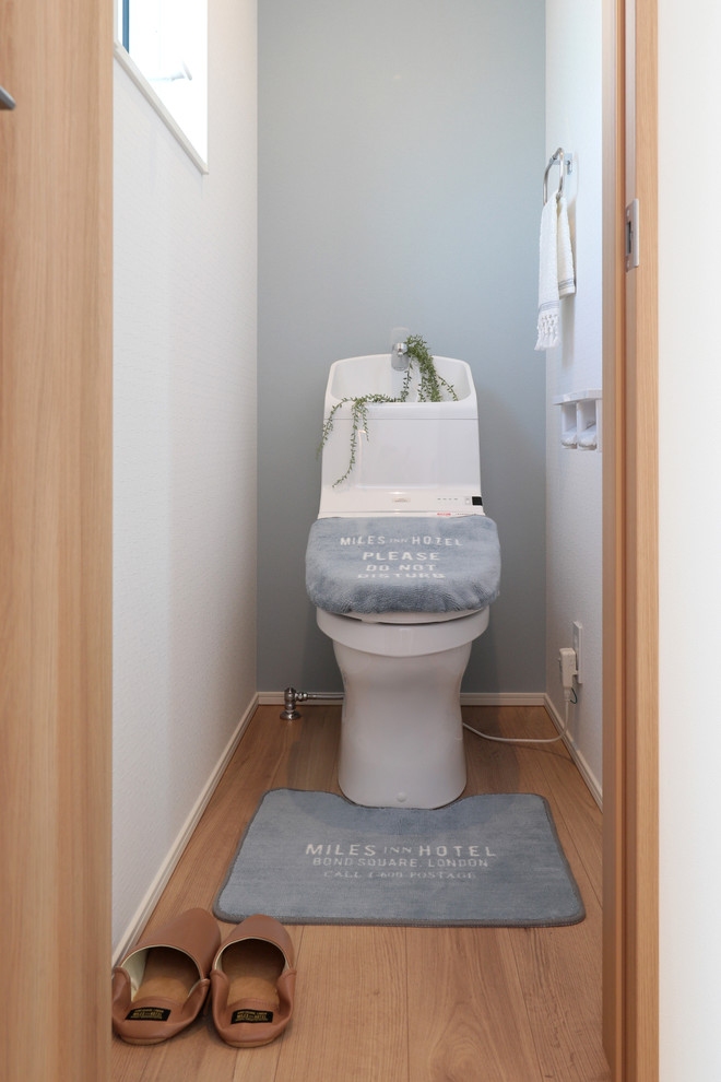 Exemple d'un petit WC et toilettes bord de mer avec un mur multicolore, parquet clair et un sol beige.