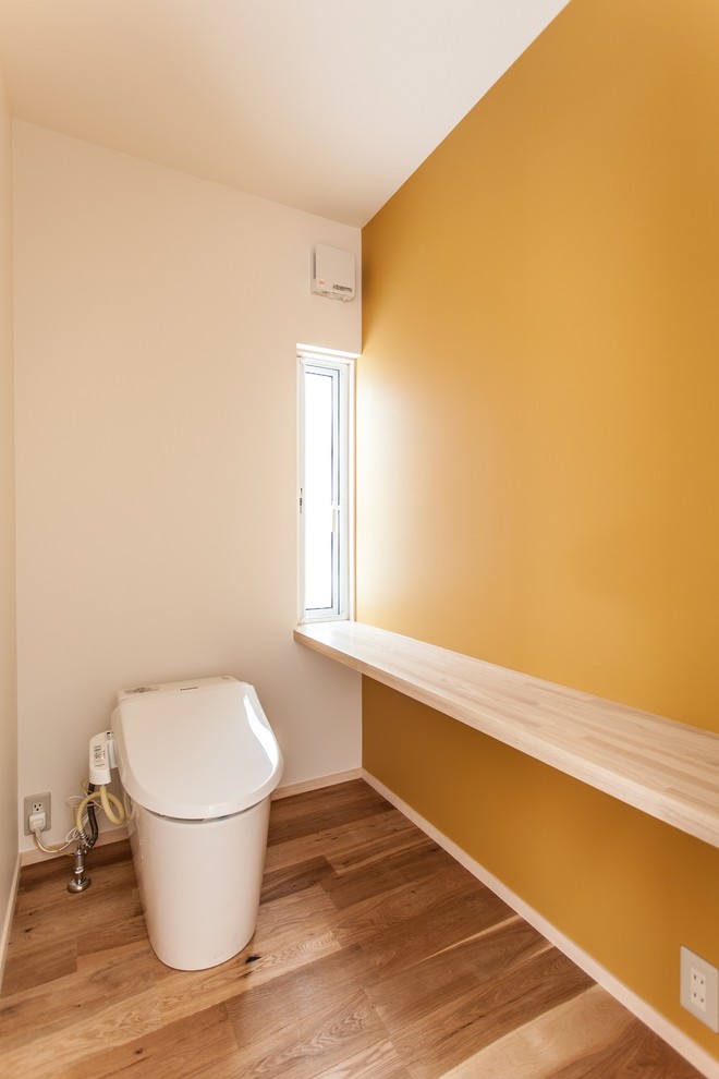 Idee per un piccolo bagno di servizio moderno con WC monopezzo, pareti bianche e pavimento in legno massello medio