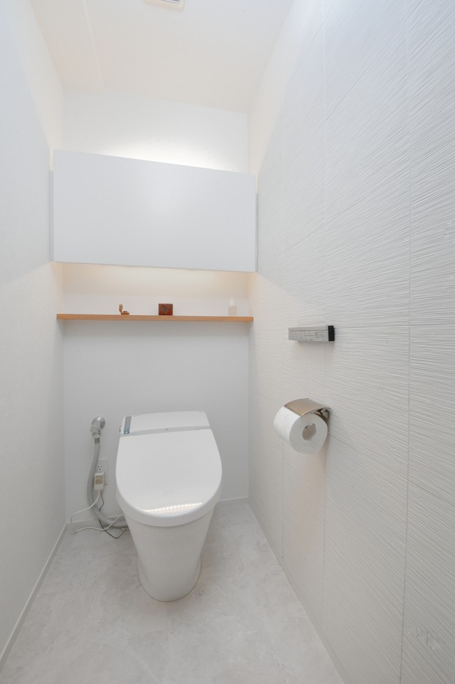 На фото: туалет в стиле модернизм с белыми стенами и белым полом с