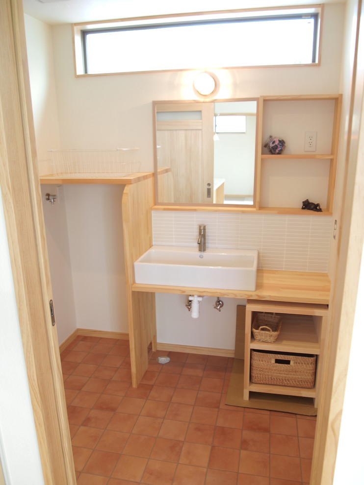 Cette photo montre un petit WC et toilettes scandinave en bois clair avec un placard sans porte, un carrelage blanc, des carreaux en allumettes et un plan de toilette beige.