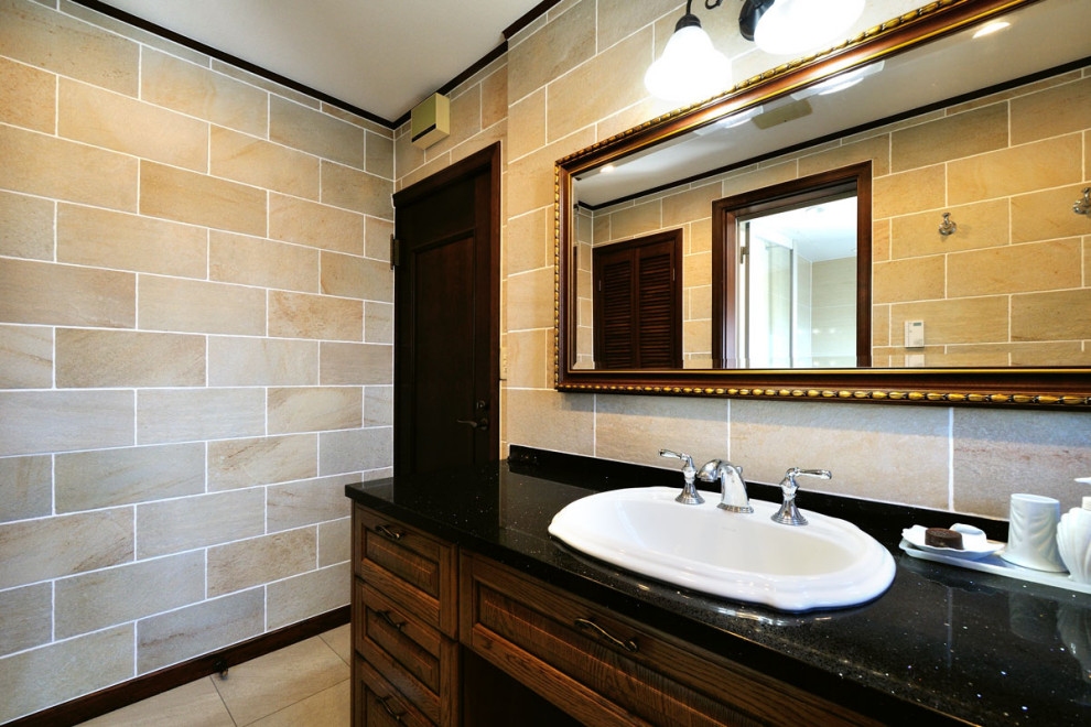 Idéer för att renovera ett mellanstort funkis svart svart toalett, med släta luckor, bruna skåp, beige kakel, porslinskakel, beige väggar, klinkergolv i porslin, ett fristående handfat, kaklad bänkskiva och svart golv