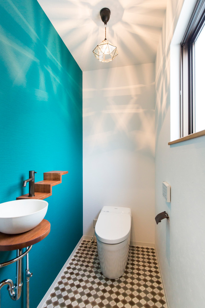 Стильный дизайн: туалет в современном стиле с синими стенами, унитазом-моноблоком, полом из мозаичной плитки, настольной раковиной и разноцветным полом - последний тренд
