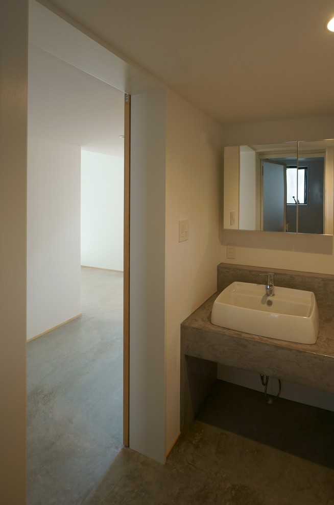 Foto de aseo moderno de tamaño medio con armarios tipo vitrina, puertas de armario blancas, paredes blancas, suelo de cemento, lavabo tipo consola y suelo gris