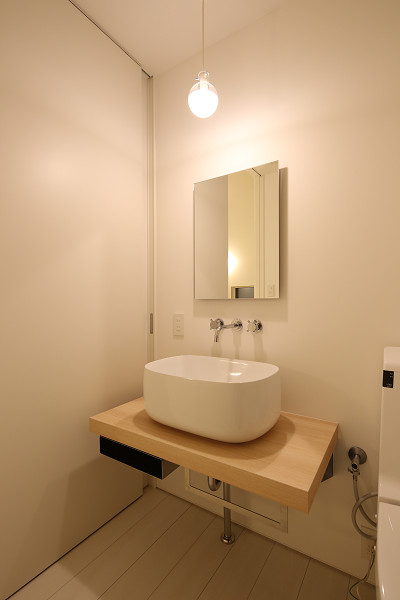 На фото: туалет среднего размера с унитазом-моноблоком, белой плиткой, плиткой из листового стекла, белыми стенами, светлым паркетным полом, врезной раковиной, столешницей из дерева и бежевым полом