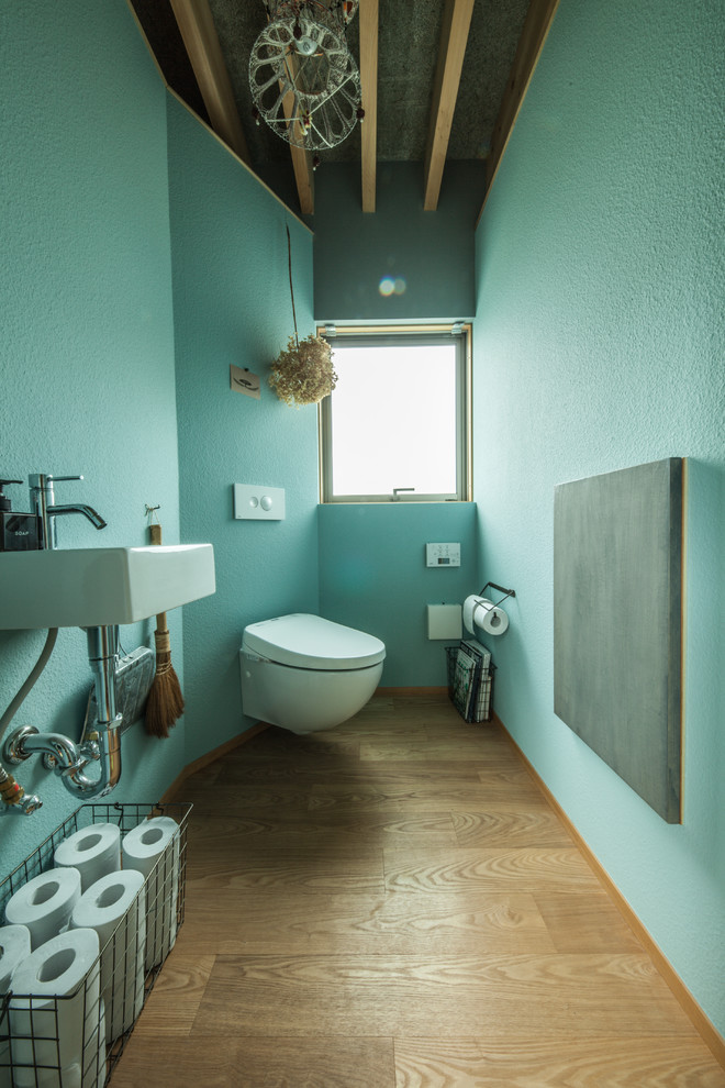 Inspiration pour un WC et toilettes asiatique avec un mur bleu, un sol en bois brun, un lavabo suspendu et un sol marron.