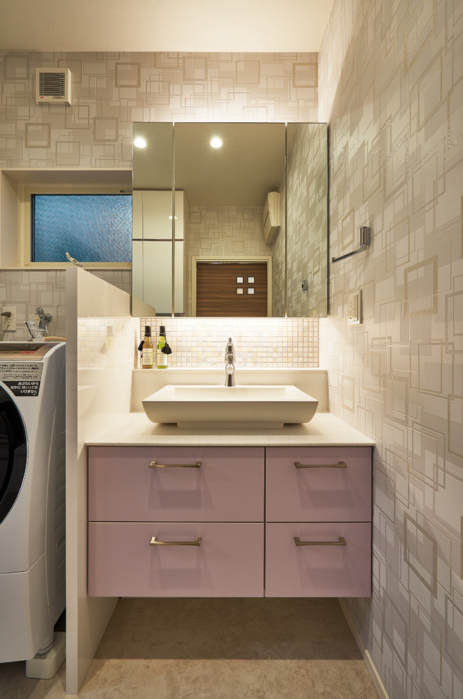 Cette image montre un petit WC et toilettes minimaliste avec un placard à porte plane, des portes de placard violettes, un mur gris, une vasque et un sol beige.