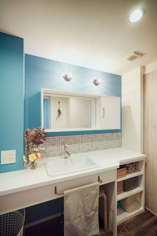 Cette image montre un WC et toilettes nordique avec un mur bleu et un lavabo posé.