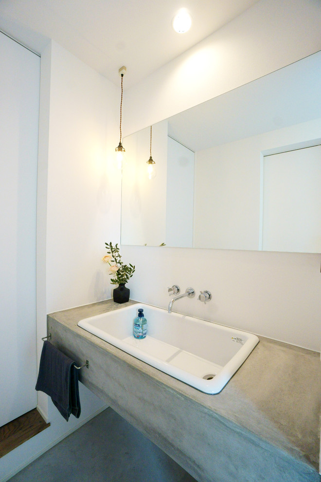 Moderne Gästetoilette mit weißer Wandfarbe, Einbauwaschbecken, Beton-Waschbecken/Waschtisch, grauem Boden und grauer Waschtischplatte in Sonstige