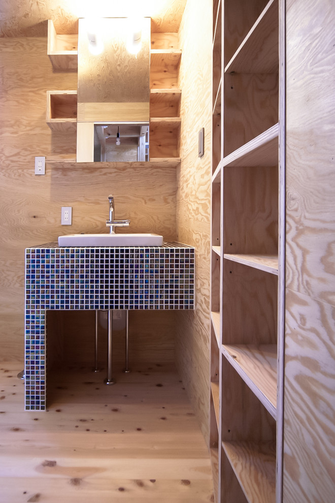 Aménagement d'un petit WC et toilettes asiatique en bois clair avec un placard sans porte, un carrelage bleu, parquet clair et un lavabo posé.