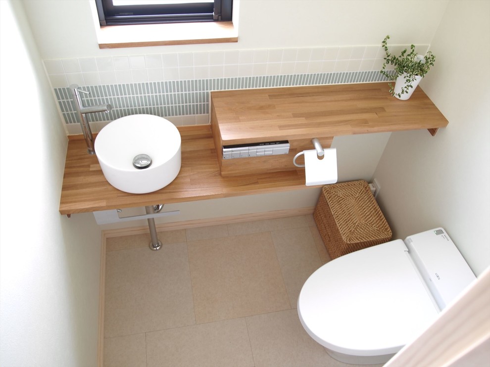 Idee per un piccolo bagno di servizio scandinavo con WC monopezzo, piastrelle bianche, piastrelle a listelli, pareti bianche, lavabo sottopiano, pavimento beige, top marrone e pavimento in vinile