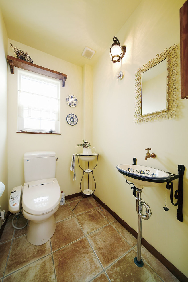 Пример оригинального дизайна: туалет в средиземноморском стиле с белыми стенами, полом из терракотовой плитки и коричневым полом