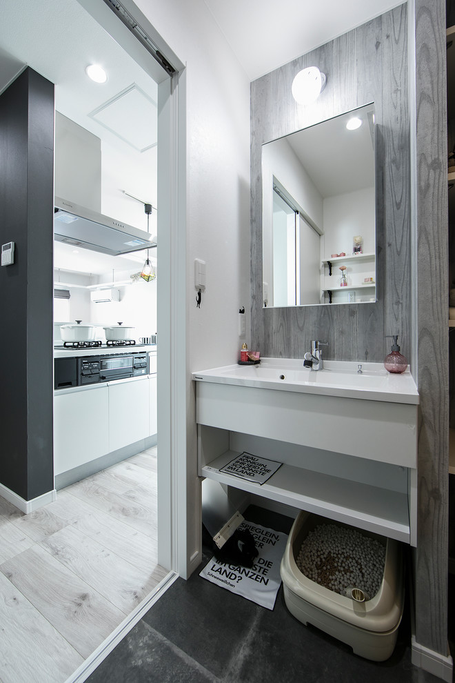 札幌にあるコンテンポラリースタイルのおしゃれなトイレ・洗面所 (マルチカラーの壁、一体型シンク、黒い床) の写真