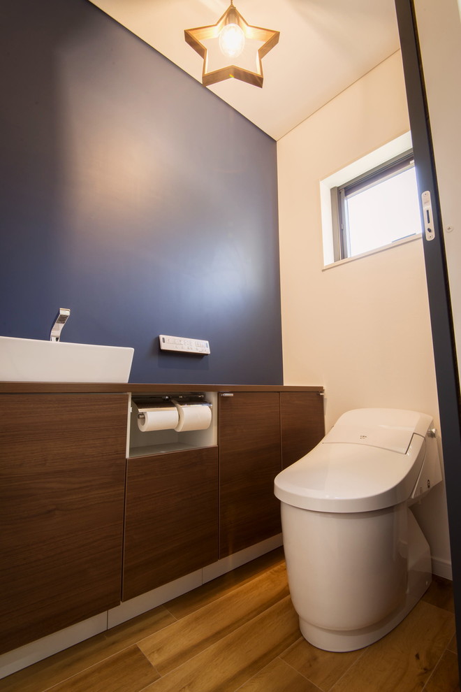 Стильный дизайн: туалет среднего размера в стиле лофт с плоскими фасадами, фасадами цвета дерева среднего тона, унитазом-моноблоком, синими стенами, светлым паркетным полом, столешницей из дерева, коричневым полом и коричневой столешницей - последний тренд