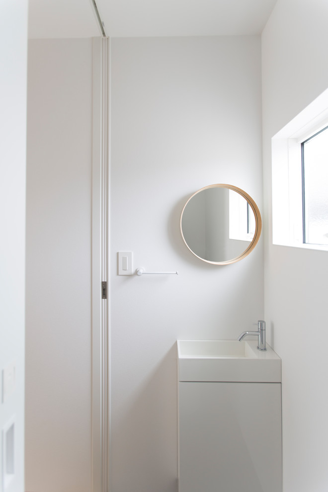 This is an example of a scandinavian cloakroom in Other with white cabinets, a one-piece toilet and white walls.