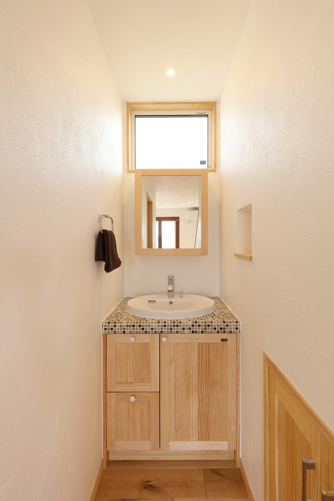 Idee per un bagno di servizio mediterraneo con pareti bianche, pavimento in legno massello medio, top piastrellato, pavimento marrone e top marrone