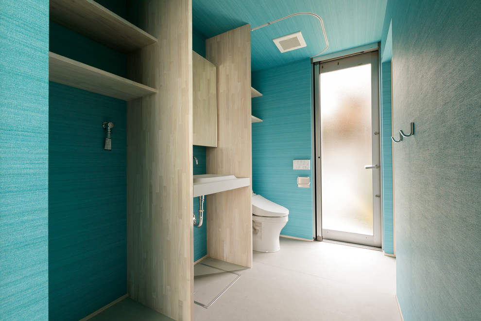 Inredning av ett modernt mellanstort vit vitt toalett, med öppna hyllor, blå väggar, betonggolv, ett integrerad handfat, grått golv, vita skåp och en toalettstol med hel cisternkåpa