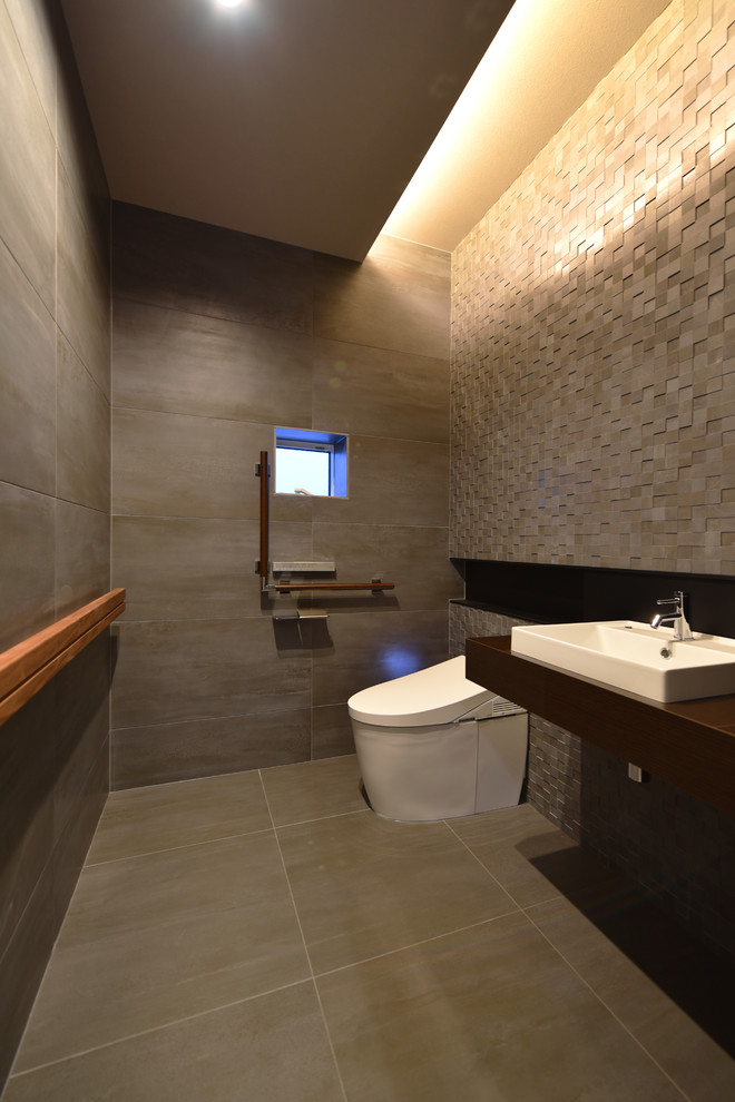 Moderne Gästetoilette mit grauer Wandfarbe, Aufsatzwaschbecken, grauem Boden und brauner Waschtischplatte