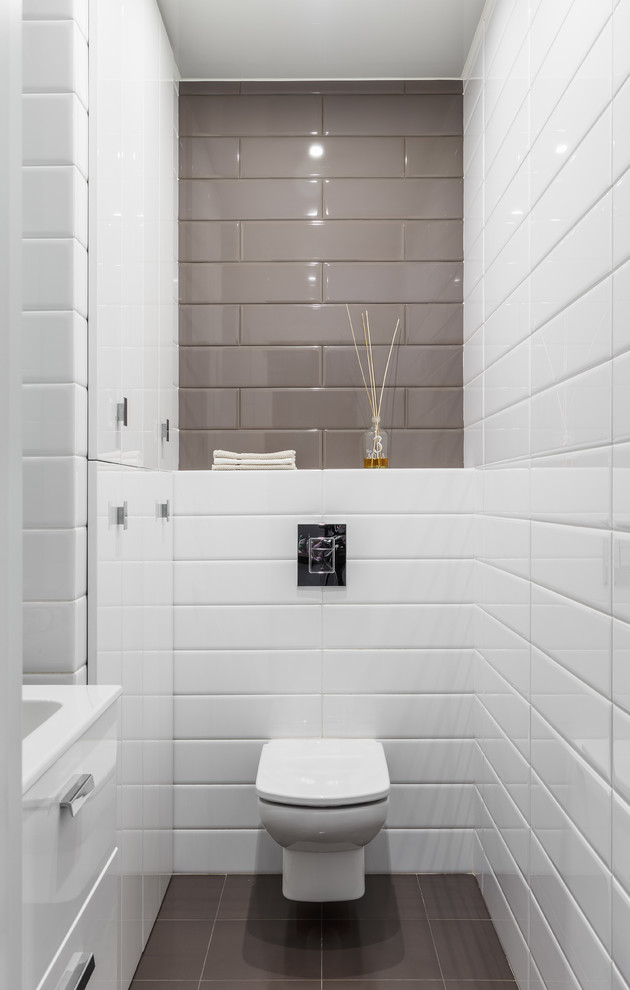 京都にあるコンテンポラリースタイルのおしゃれなトイレ・洗面所 (フラットパネル扉のキャビネット、白いキャビネット、壁掛け式トイレ、グレーのタイル、白いタイル、サブウェイタイル、マルチカラーの壁、グレーの床) の写真