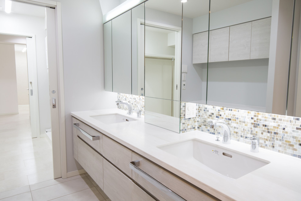 Inspiration for a large contemporary cloakroom in Tokyo with glass-front cabinets, white cabinets, grey tiles, glass tiles, white walls, ceramic flooring, a submerged sink, solid surface worktops, beige floors, white worktops, a floating vanity unit and a wallpapered ceiling.