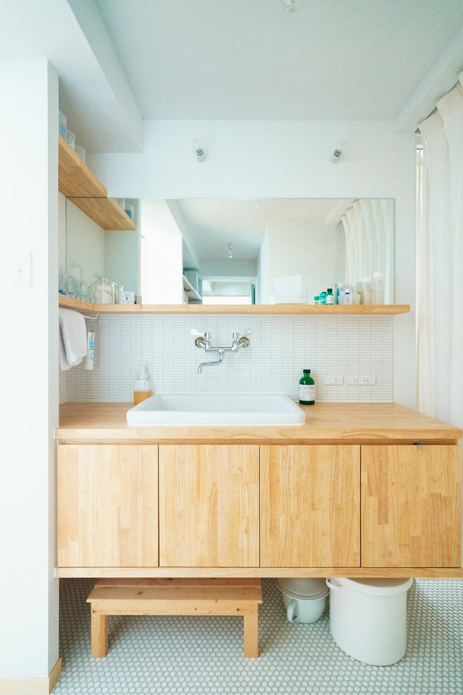 名古屋にあるアジアンスタイルのおしゃれなトイレ・洗面所 (フラットパネル扉のキャビネット、中間色木目調キャビネット、白いタイル、白い壁、オーバーカウンターシンク、白い床) の写真