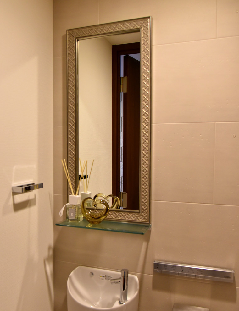 Exemple d'un WC et toilettes avec WC à poser, des carreaux de céramique, un mur beige, un sol en carrelage de céramique, un lavabo suspendu et un sol blanc.