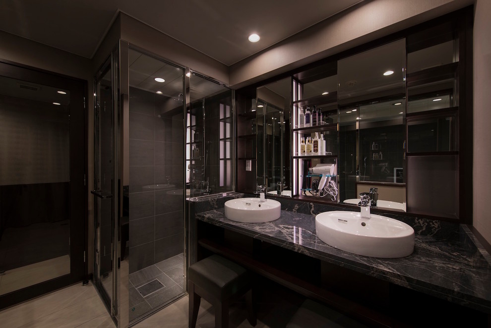 Cette image montre un WC et toilettes minimaliste avec un placard sans porte, des portes de placard noires, un carrelage gris, des carreaux de porcelaine, un mur gris, un sol en carrelage de porcelaine, une vasque et un plan de toilette en marbre.