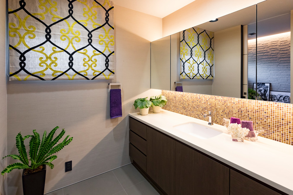 Источник вдохновения для домашнего уюта: туалет в современном стиле с плоскими фасадами, серыми стенами, серым полом, коричневыми фасадами, разноцветной плиткой, плиткой мозаикой, врезной раковиной и белой столешницей