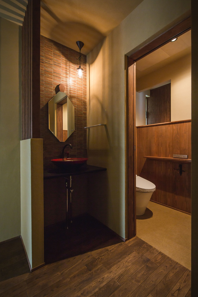 Exemple d'un WC et toilettes asiatique avec un mur marron, parquet foncé, un plan vasque et un sol marron.