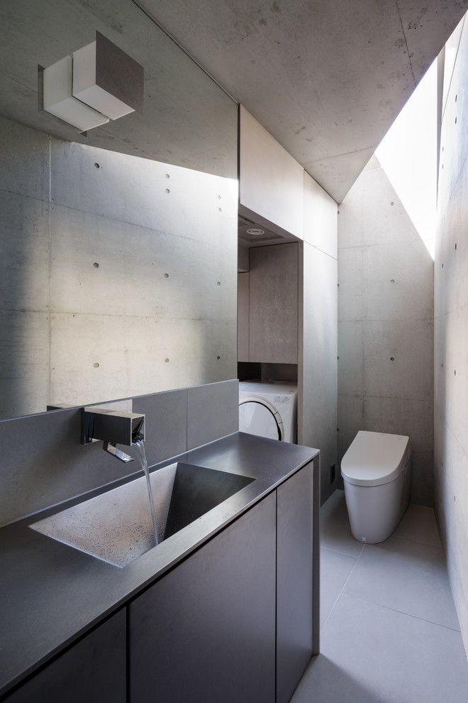 Moderne Gästetoilette mit flächenbündigen Schrankfronten, integriertem Waschbecken, Toilette mit Aufsatzspülkasten und grauem Boden in Tokio