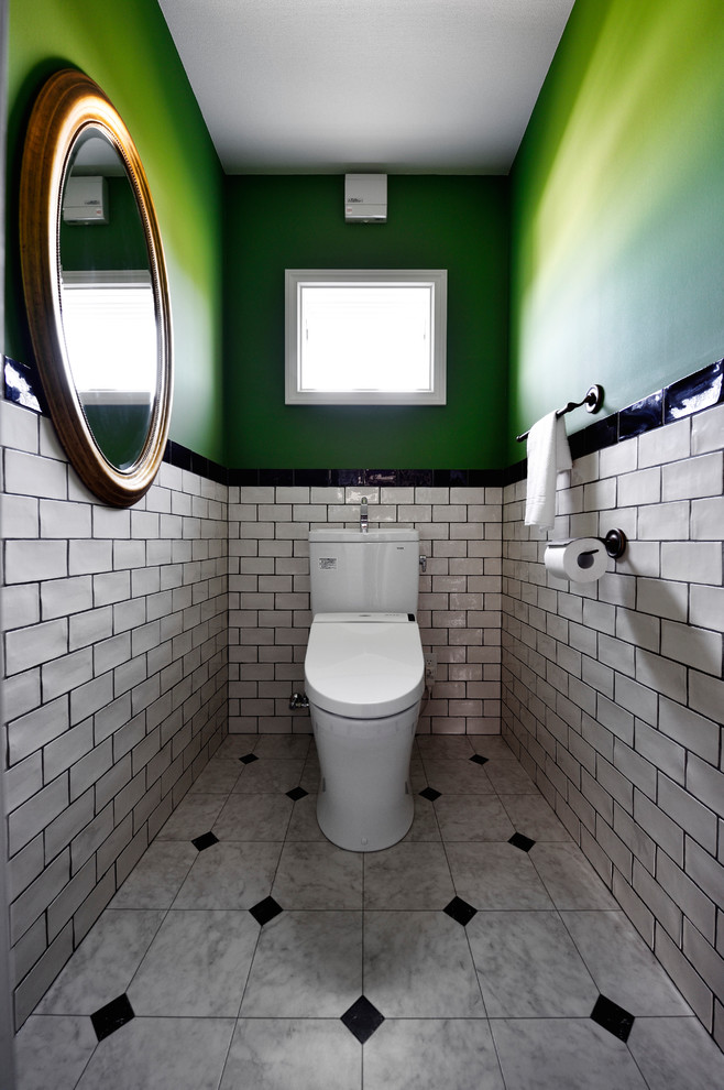 На фото: туалет в современном стиле с унитазом-моноблоком, черно-белой плиткой, белой плиткой, зелеными стенами и разноцветным полом
