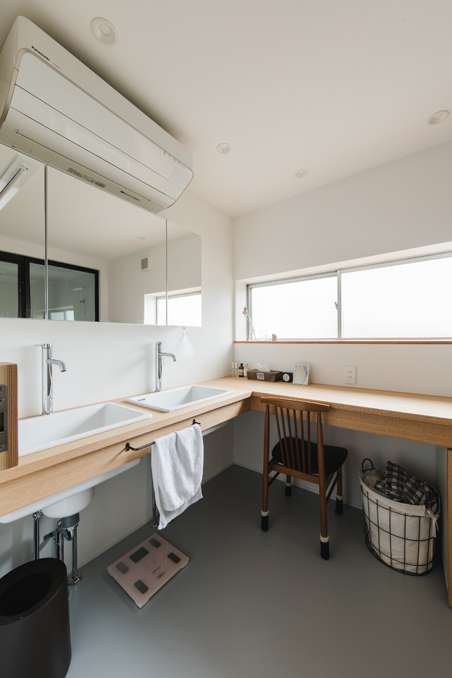 This is an example of an expansive world-inspired cloakroom in Other with white walls, a built-in sink, wooden worktops, grey floors, brown worktops, open cabinets, beige cabinets and concrete flooring.