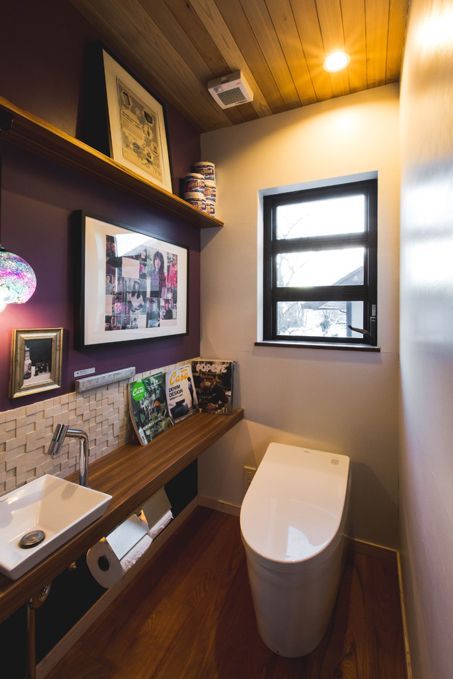 他の地域にある北欧スタイルのおしゃれなトイレ・洗面所 (一体型トイレ	、紫の壁、濃色無垢フローリング、茶色い床、ベッセル式洗面器、木製洗面台、ブラウンの洗面カウンター) の写真