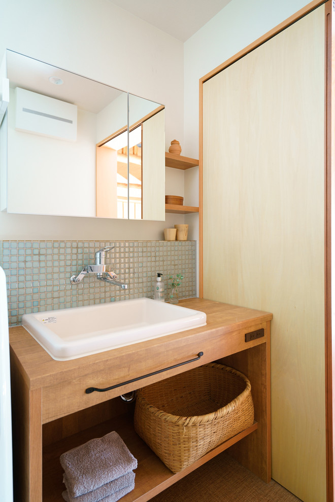 Asiatische Gästetoilette mit offenen Schränken, hellbraunen Holzschränken, weißer Wandfarbe, Aufsatzwaschbecken und Waschtisch aus Holz in Nagoya