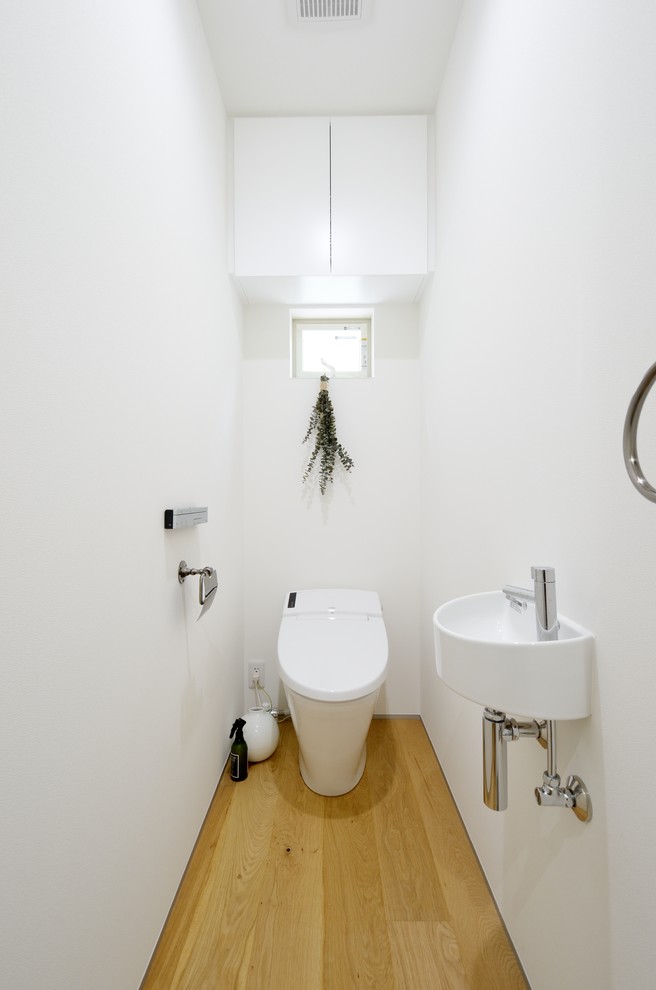 東京23区にあるモダンスタイルのおしゃれなトイレ・洗面所 (白いキャビネット、一体型トイレ	、白い壁、淡色無垢フローリング、人工大理石カウンター、白い床、白い洗面カウンター) の写真