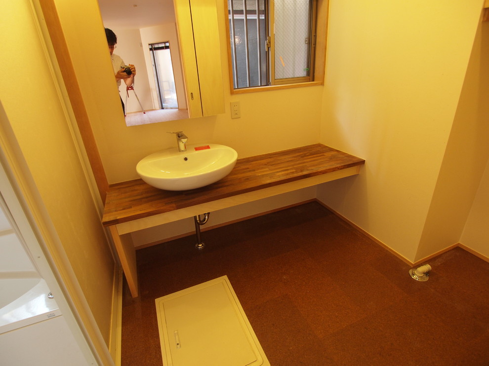 Cette image montre un petit WC et toilettes traditionnel avec un mur beige, une vasque et un plan de toilette en bois.