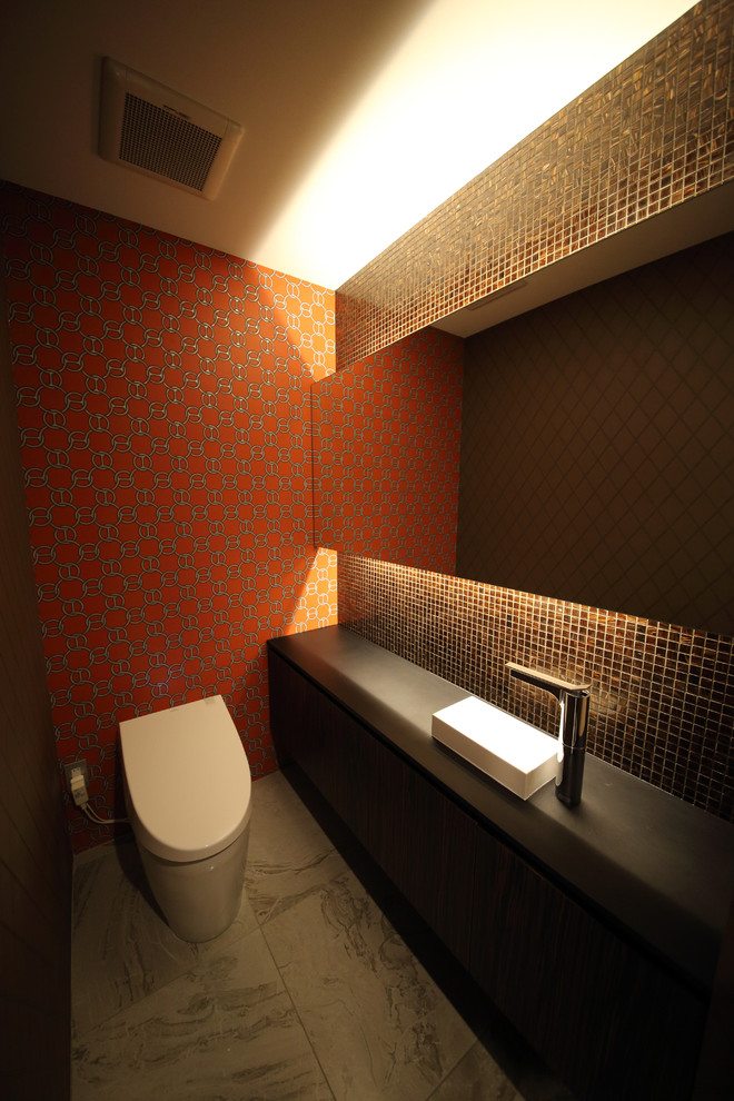 Immagine di un bagno di servizio minimalista con piastrelle marroni, pareti multicolore e lavabo da incasso