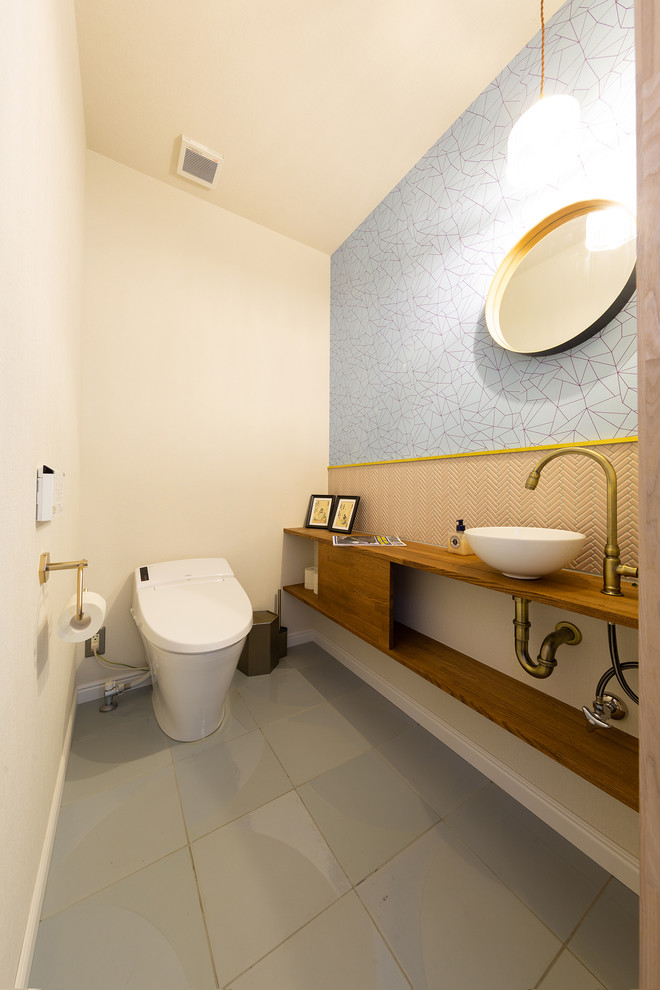 Exemple d'un WC et toilettes tendance avec un placard sans porte, un carrelage rose, mosaïque, un mur blanc, un sol en carrelage de céramique, un lavabo posé, un plan de toilette en bois et un plan de toilette marron.