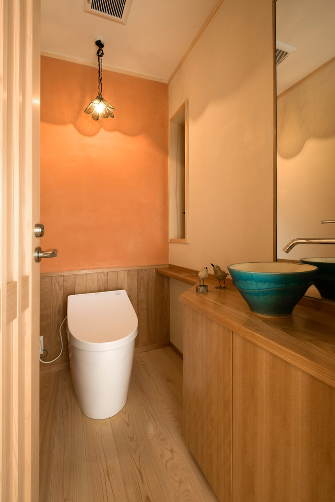 Idéer för vintage toaletter, med släta luckor, skåp i mellenmörkt trä, orange väggar, målat trägolv, ett fristående handfat och brunt golv