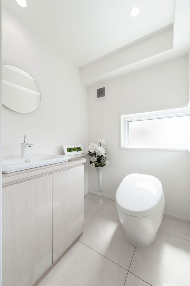 Идея дизайна: туалет в стиле модернизм с плоскими фасадами, белыми фасадами, белыми стенами, настольной раковиной и белым полом
