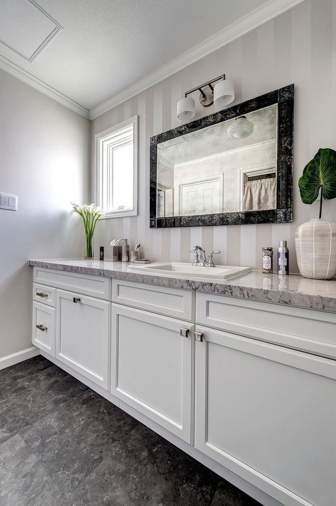 Powder room - transitional brown floor powder room idea in Other with recessed-panel cabinets, white cabinets, gray walls, a drop-in sink and marble countertops