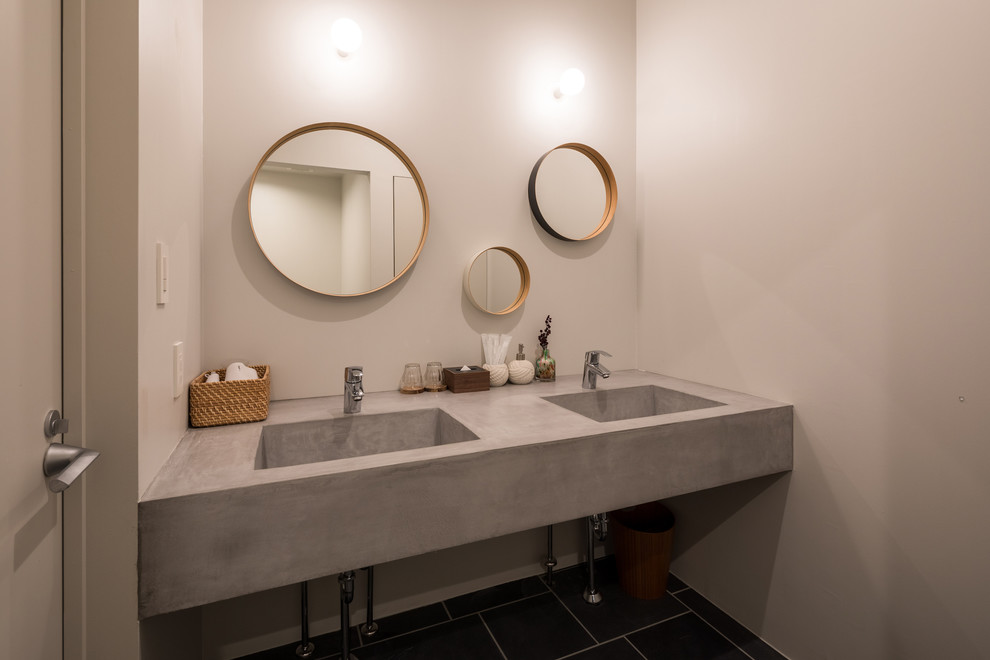 На фото: туалет в современном стиле с серыми стенами, монолитной раковиной и черным полом