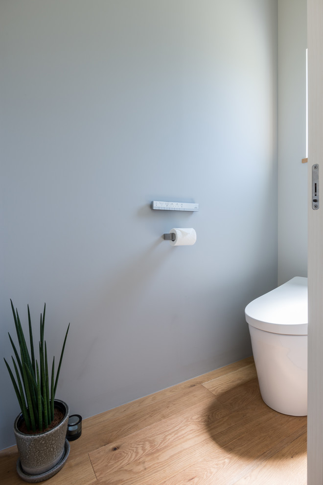 Réalisation d'un WC et toilettes design avec un mur bleu, un sol en bois brun et un sol marron.