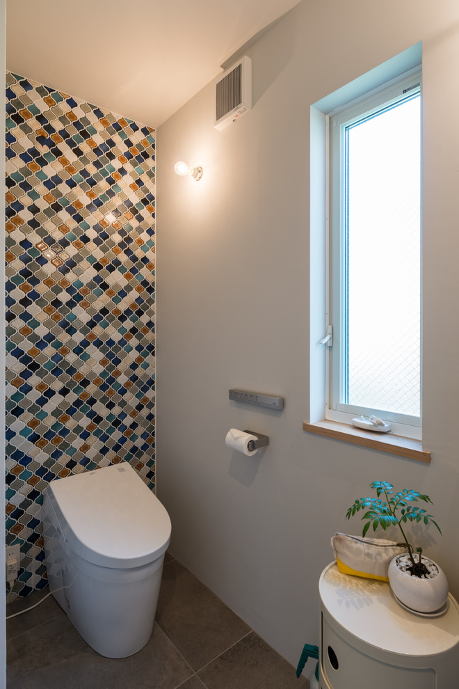 他の地域にあるコンテンポラリースタイルのおしゃれなトイレ・洗面所 (グレーの壁、茶色い床) の写真
