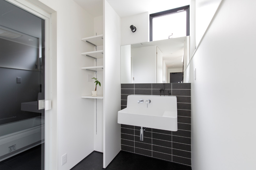 Idées déco pour un WC et toilettes moderne avec un mur blanc, un lavabo suspendu et un sol noir.