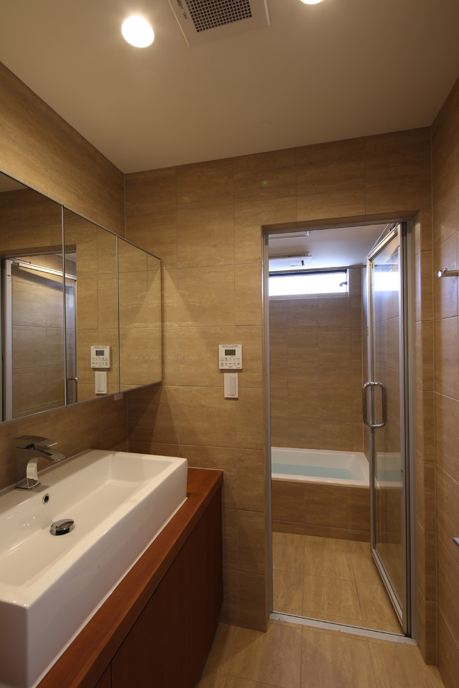 Réalisation d'un petit WC et toilettes asiatique en bois brun avec un placard à porte affleurante, un carrelage beige, des carreaux de béton, un mur beige, un sol en carrelage de céramique, une vasque, un sol beige et un plan de toilette marron.