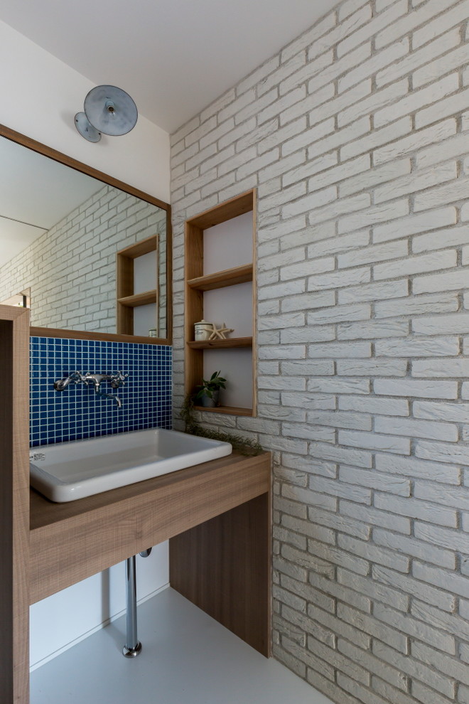 This is an example of a medium sized world-inspired cloakroom in Kyoto with open cabinets, medium wood cabinets, a two-piece toilet, white tiles, porcelain tiles, white walls, concrete flooring, a vessel sink, laminate worktops, grey floors and beige worktops.