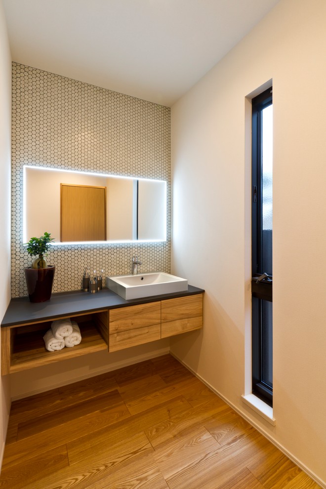 Example of a trendy white tile medium tone wood floor and brown floor powder room design in Other with flat-panel cabinets, dark wood cabinets, white walls and a vessel sink