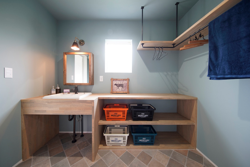 Idee per un bagno di servizio stile marinaro con nessun'anta, ante in legno chiaro, pareti blu, lavabo da incasso, top in legno, pavimento beige e top beige