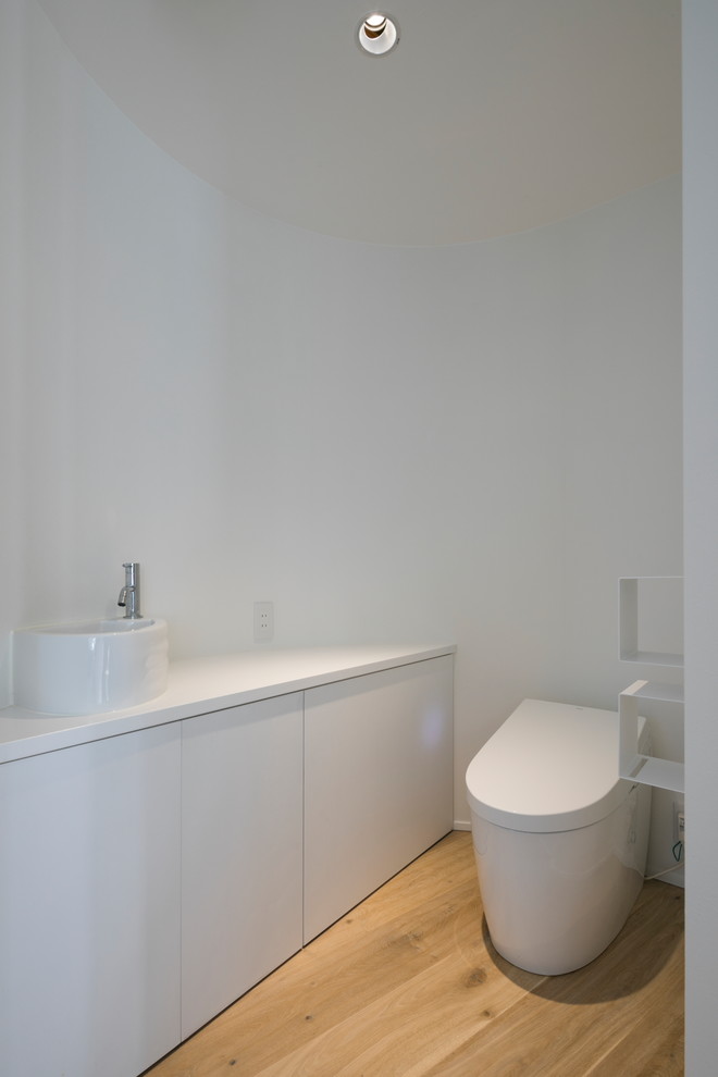 横浜にあるモダンスタイルのおしゃれなトイレ・洗面所 (フラットパネル扉のキャビネット、白いキャビネット、白い壁、無垢フローリング、ベッセル式洗面器、茶色い床) の写真