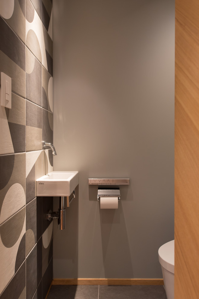 На фото: туалет в восточном стиле с черно-белой плиткой, керамической плиткой, серыми стенами, подвесной раковиной и серым полом